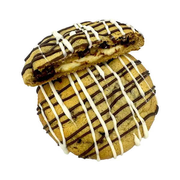 A creamy cheesecake filling stuffed inside a giant chocolate chip cookie, drizzled with white and milk chocolate