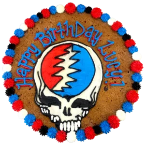 Giant chocolate chip flavored cookie cake brightly decorated with a frosted border and happy birthday text.