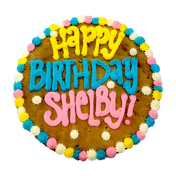 Giant chocolate chip cookie cake, frosted with a bright and colorful border and text that says "happy birthday Shelby".