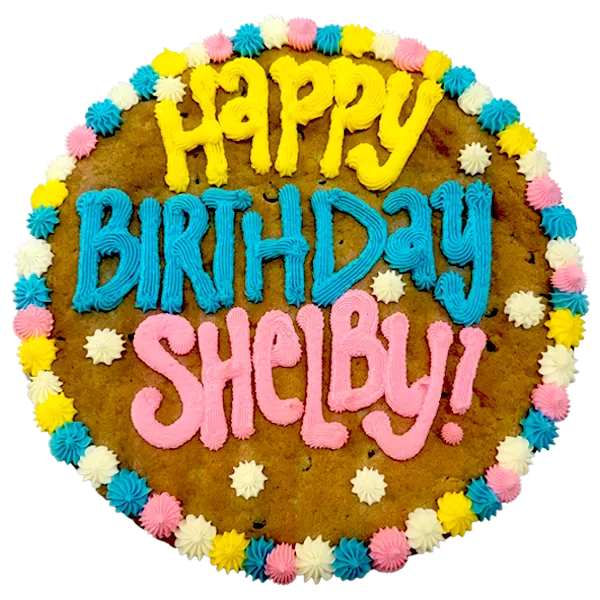 Giant chocolate chip cookie cake, frosted with a bright and colorful border and text that says "happy birthday Shelby".
