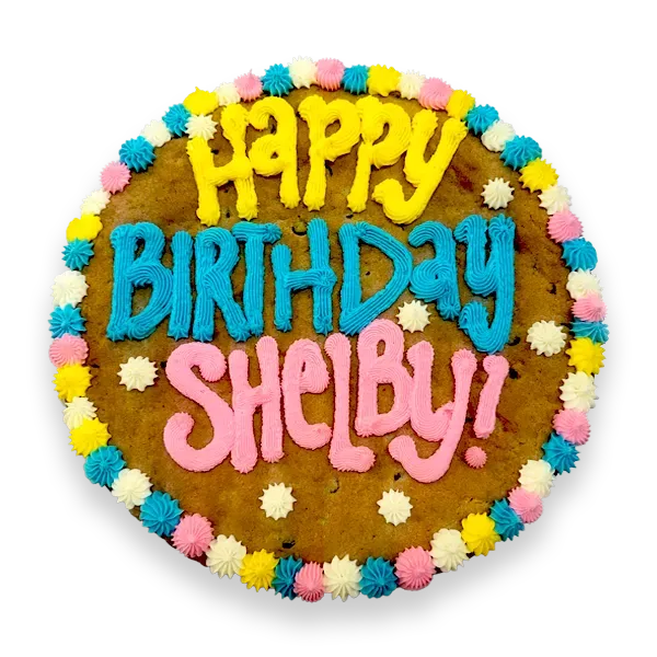 Giant chocolate chip cookie cake, frosted with a bright and colorful border and text that says "happy birthday Shelby".