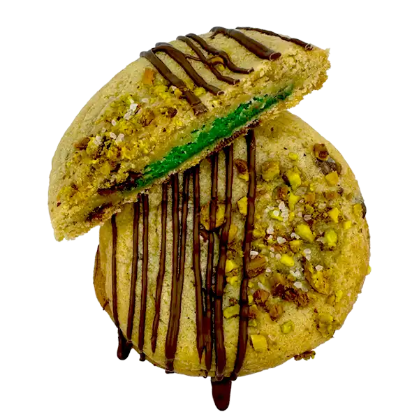 Our homemade pistachio cookie butter stuffed between two chocolate chip cookies, rolled in chopped pistachios and sea salt, and then finished off with an extra drizzle of milk chocolate!