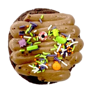 Giant chocolate boneyard cookie topped with chocolate mousse, candy bones, candy eyes, and a tombstone decoration for Halloween.