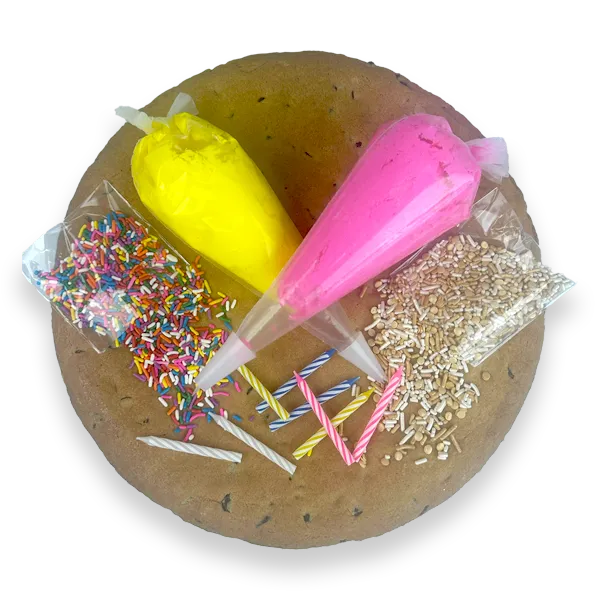 Cookie Cake Decorating Kit with a 12-inch diameter plain round chocolate chip cookie cake, 2-icing bags, 2-bags of sprinkles, and colorful candles for decorating at home.