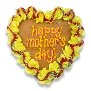 Heart-shaped Mother's Day cookie cake decorated with yellow buttercream rosettes, colorful sprinkles, and a hand-piped "happy mother's day!" message in pink and orange lettering.