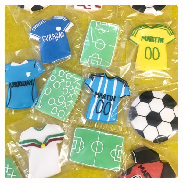 Custom soccer themed decorated sugar cookies featuring personalized jerseys, soccer balls, and field designs
