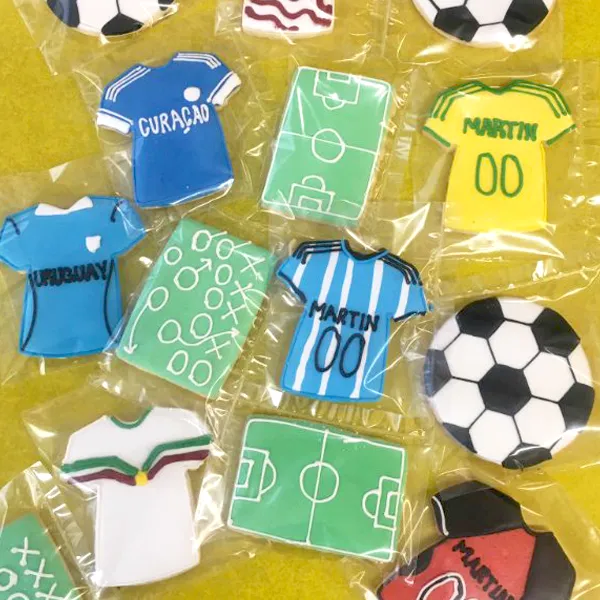 Custom soccer themed decorated sugar cookies featuring personalized jerseys, soccer balls, and field designs